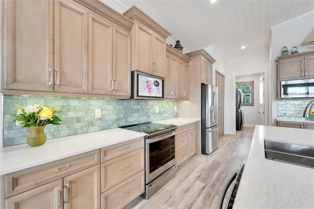 kitchen featuring stainless steel appliances, light hardwood / wood-style floors, lofted ceiling, light brown cabinets, and tasteful backsplash