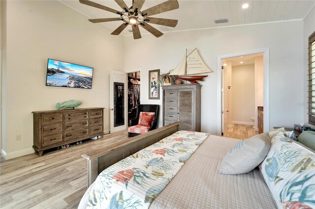 bedroom with light wood-type flooring, ceiling fan, ensuite bathroom, and vaulted ceiling