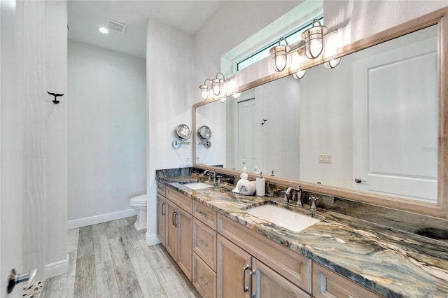 bathroom featuring wood finished floors, a sink, toilet, and baseboards