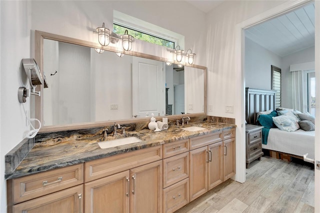 ensuite bathroom with plenty of natural light, a sink, and wood finished floors