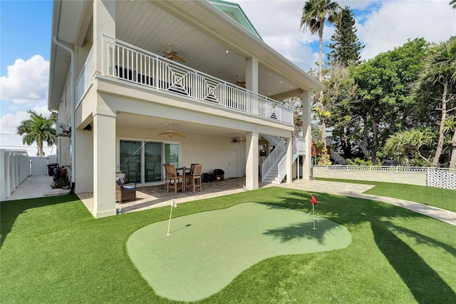 rear view of property featuring a balcony, ceiling fan, a yard, and a patio area