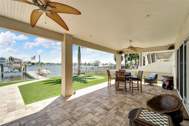 view of patio featuring ceiling fan, a boat dock, a water view, and a fenced backyard