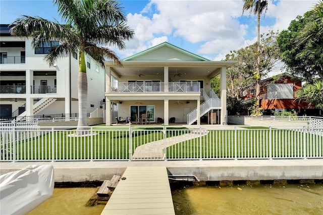 rear view of property featuring a balcony, a water view, and a lawn