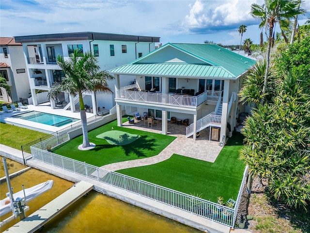 rear view of house with metal roof, a lawn, a patio area, and a fenced backyard