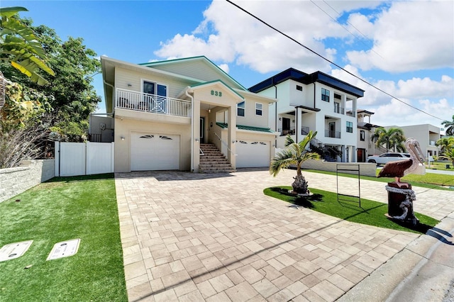 view of front of home with an attached garage, fence, a front lawn, and decorative driveway