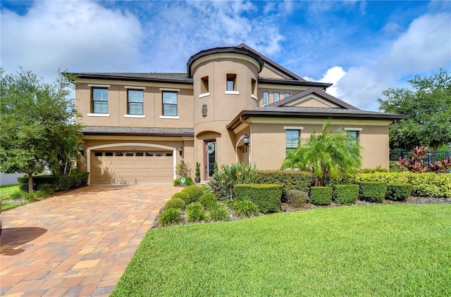 mediterranean / spanish home with a front yard, decorative driveway, an attached garage, and stucco siding