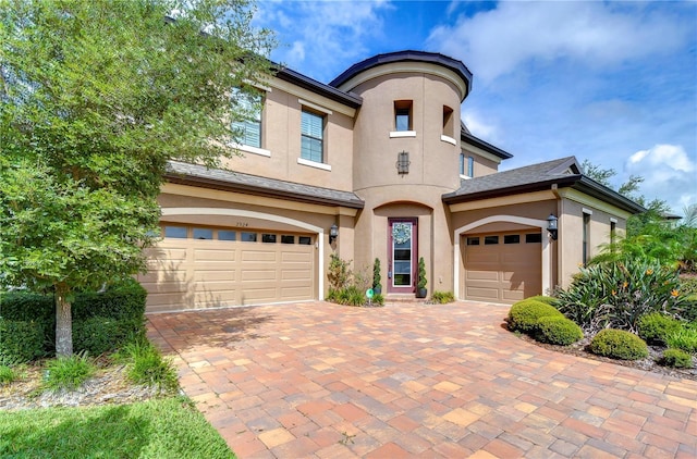 view of front of property with stucco siding, decorative driveway, and a garage