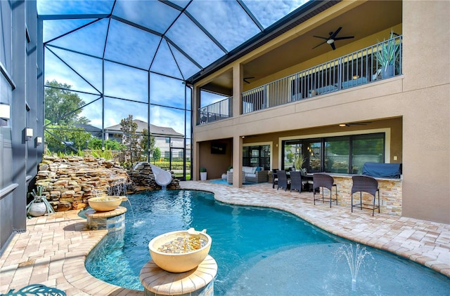 view of pool featuring pool water feature, ceiling fan, a patio, and glass enclosure