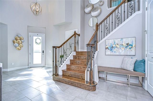 tiled entrance foyer featuring a high ceiling and a chandelier