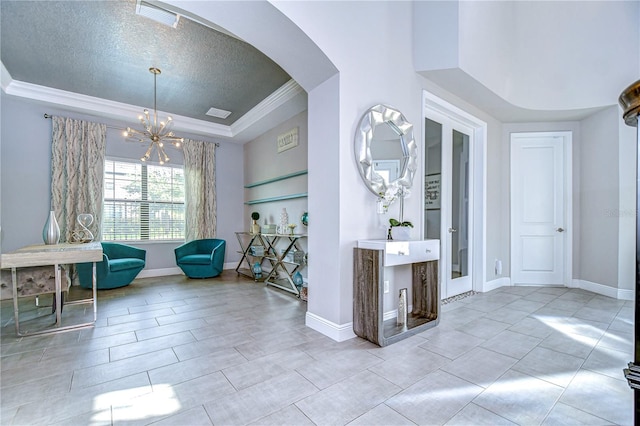 tiled foyer with a textured ceiling, crown molding, and an inviting chandelier