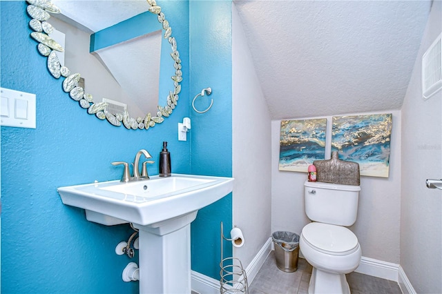 bathroom featuring lofted ceiling, tile patterned floors, toilet, and a textured ceiling