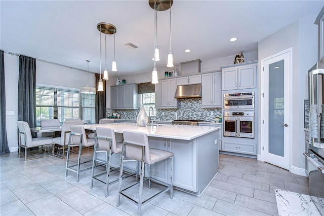 kitchen with plenty of natural light, pendant lighting, a breakfast bar, and an island with sink