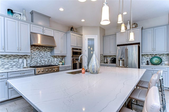 kitchen with appliances with stainless steel finishes, pendant lighting, a center island with sink, and decorative backsplash