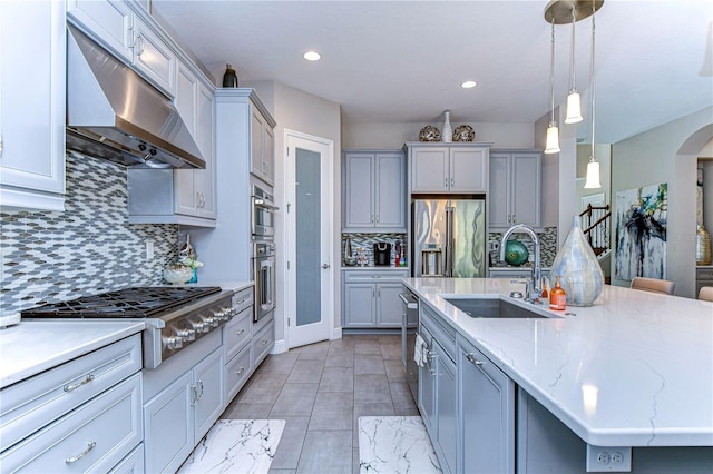 kitchen with decorative light fixtures, tasteful backsplash, an island with sink, stainless steel appliances, and sink