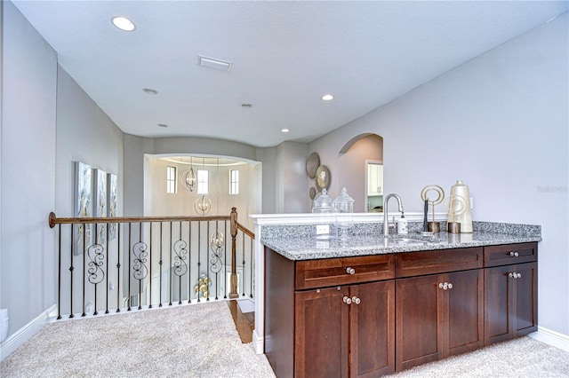 kitchen featuring light stone counters, light carpet, and sink