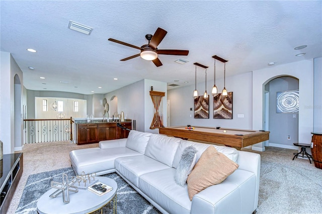 carpeted living room with billiards, ceiling fan, and a textured ceiling