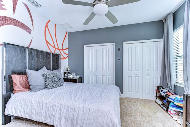 bedroom featuring two closets, ceiling fan, and carpet flooring