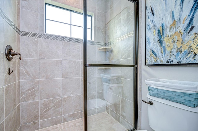 bathroom featuring a shower with shower door and toilet