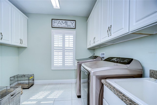 clothes washing area featuring cabinets, washer and dryer, and light tile patterned flooring