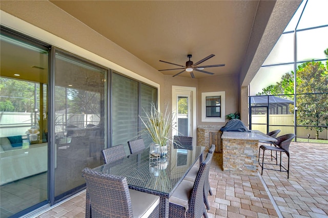 view of patio with area for grilling, ceiling fan, and glass enclosure