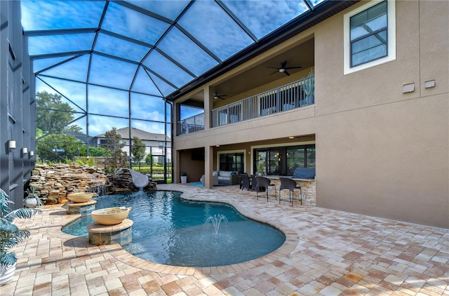 view of swimming pool featuring glass enclosure, a patio, ceiling fan, and pool water feature