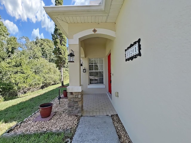 property entrance featuring stucco siding and a lawn