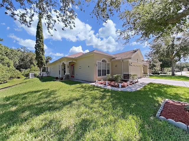 view of front of property featuring stucco siding, a front yard, a garage, and driveway