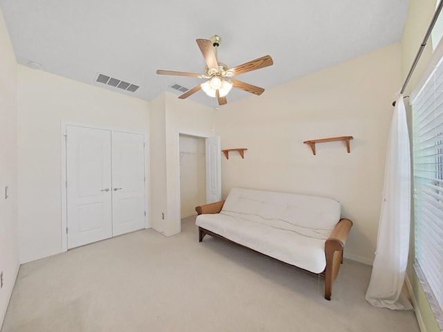 living area featuring visible vents, light carpet, and ceiling fan