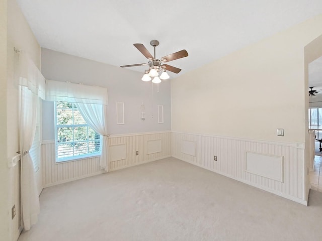 spare room with a wainscoted wall, ceiling fan, and carpet