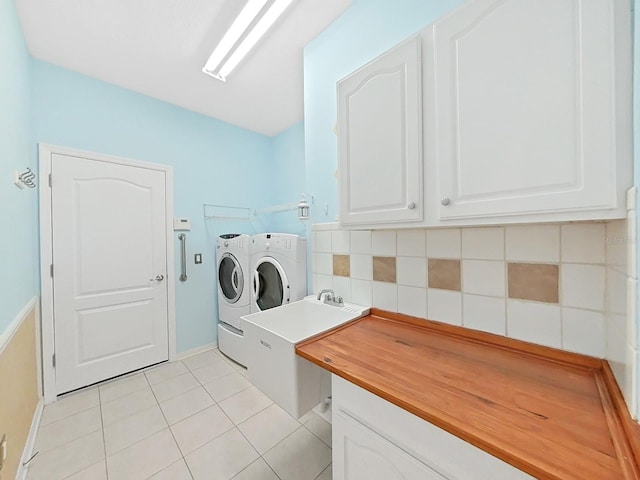 clothes washing area featuring light tile patterned floors, cabinet space, and independent washer and dryer