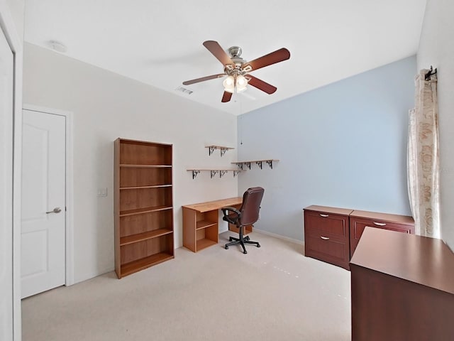 office area featuring a ceiling fan, visible vents, and light carpet