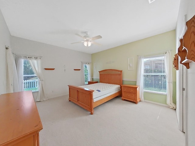 bedroom featuring baseboards, light colored carpet, and ceiling fan