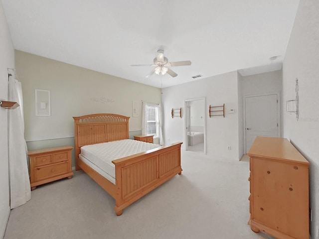 bedroom featuring ensuite bath, light colored carpet, visible vents, and ceiling fan