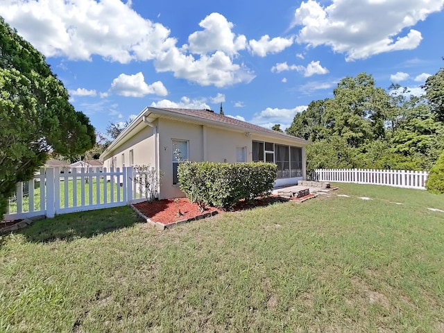 view of side of property featuring stucco siding, a lawn, and fence