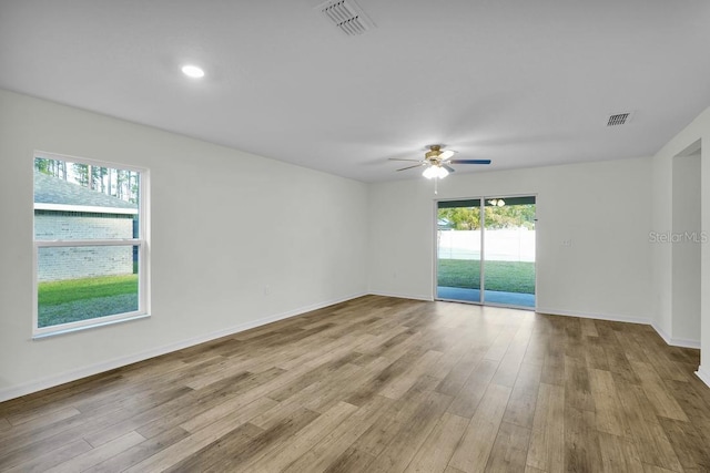 unfurnished room with wood finished floors, visible vents, and baseboards