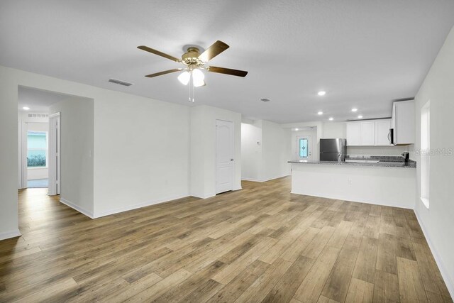 unfurnished living room with light hardwood / wood-style flooring and ceiling fan