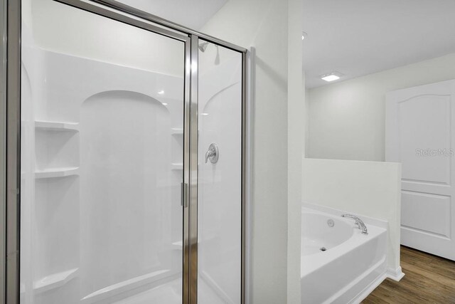 bathroom with wood-type flooring and shower with separate bathtub