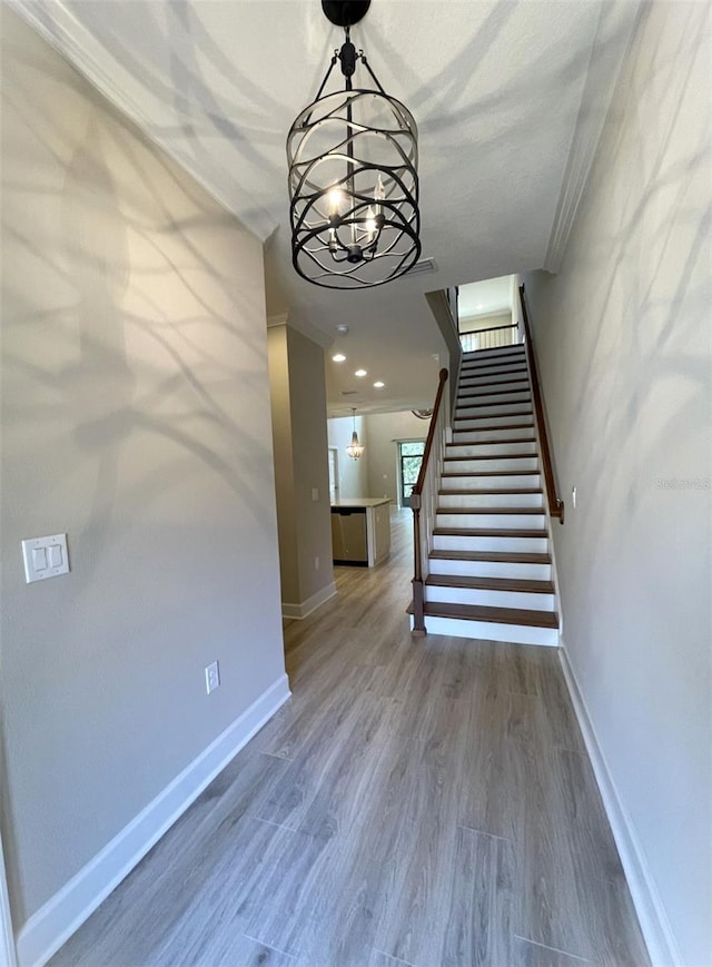 staircase featuring a notable chandelier, crown molding, and wood-type flooring