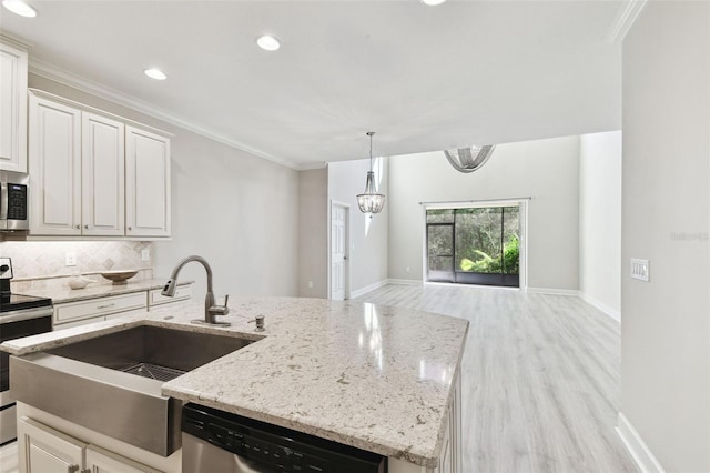 kitchen with tasteful backsplash, white cabinetry, light wood-type flooring, an island with sink, and stainless steel appliances