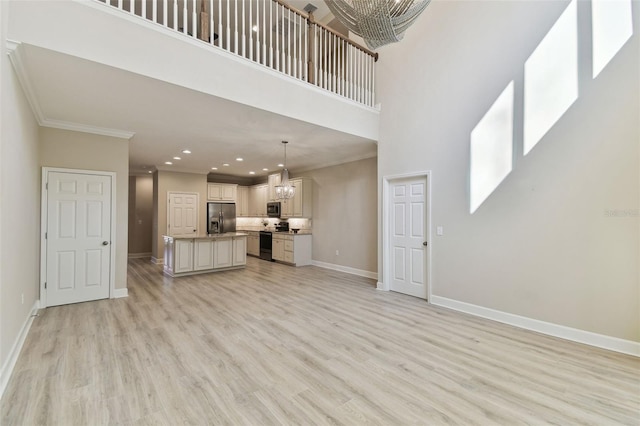 unfurnished living room with crown molding, a towering ceiling, and light wood-type flooring