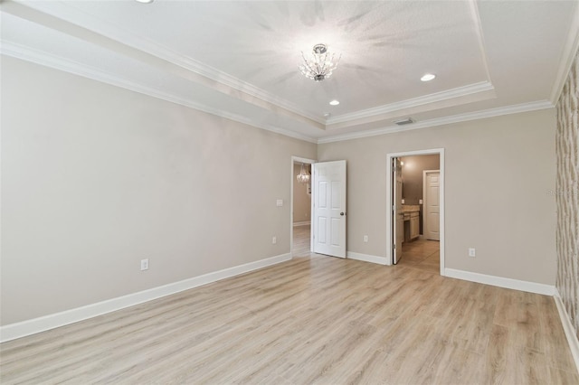 unfurnished bedroom with light hardwood / wood-style flooring, connected bathroom, a tray ceiling, and ornamental molding