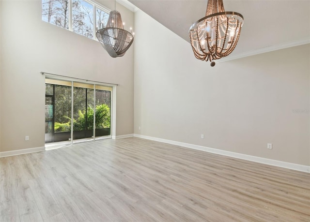 interior space with light hardwood / wood-style floors, a high ceiling, ornamental molding, and a chandelier