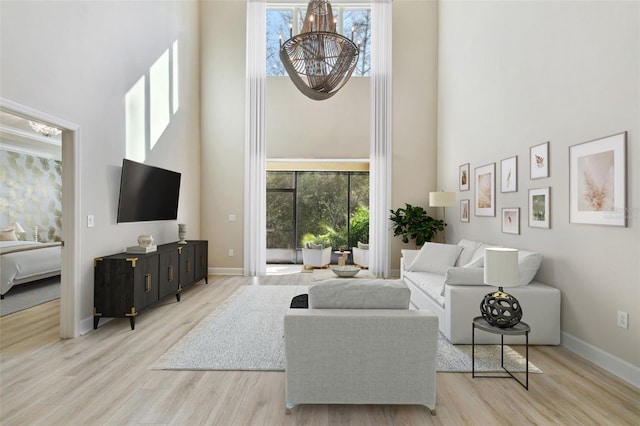 living room with a high ceiling, light hardwood / wood-style flooring, and a chandelier