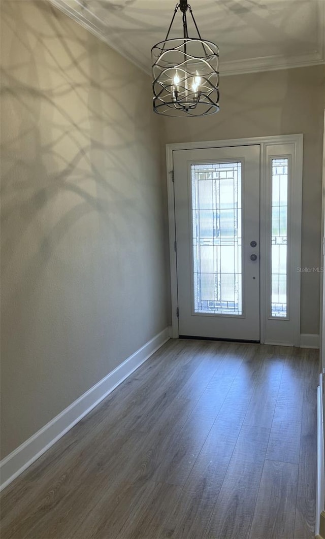 entrance foyer with dark hardwood / wood-style flooring, a chandelier, and ornamental molding