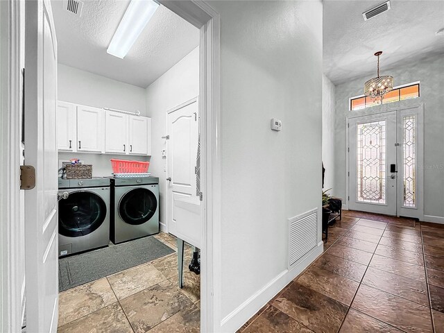 laundry area with independent washer and dryer, an inviting chandelier, cabinets, and a textured ceiling