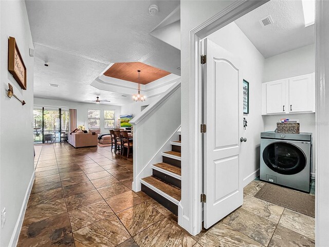 laundry area with ceiling fan with notable chandelier, a textured ceiling, cabinets, and washer / clothes dryer