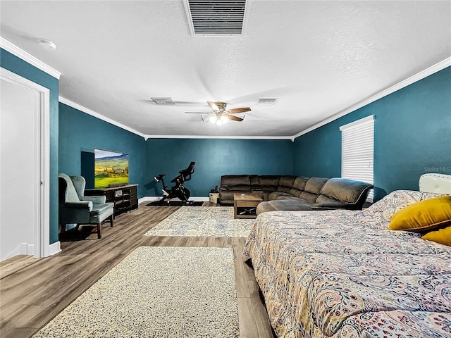 bedroom featuring wood-type flooring, ornamental molding, a textured ceiling, and ceiling fan