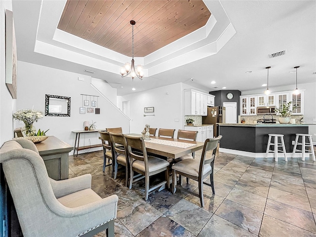 dining area featuring a tray ceiling, an inviting chandelier, and wooden ceiling