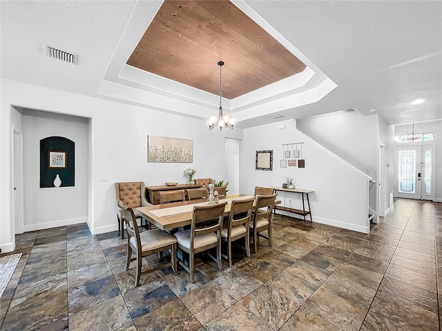 dining area featuring a textured ceiling, french doors, an inviting chandelier, and a tray ceiling