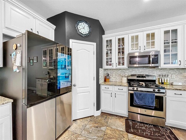 kitchen with appliances with stainless steel finishes, light stone counters, and white cabinetry